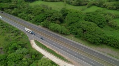 Panama kırsalından kargo taşıyan bir yük kamyonunun insansız hava aracı bakış açısı. Büyük bir tırın üzerinde uçuyor. 18 tekerli Panamerikan otoyolunda ilerliyor. Etrafı yemyeşil yağmur ormanlarıyla çevrili..