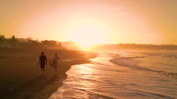 Aerial Silhouette 两名冲浪者背着冲浪板在海滩上行走 在早上冲浪课之前 冲浪夫妇在金色的阳光下聊天 巴拿马Playa Venao美丽的夏季风景 — 图库视频影像