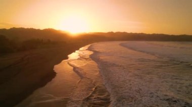 Otobanda ilerleyen arabanın arka camında altın güneş ışınları parlıyor..