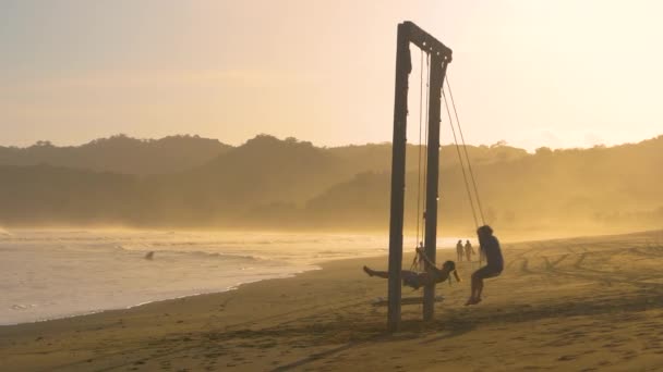 Moving Shot Two Friends Big Swing Misty Tropical Beach Sunset — Stock Video