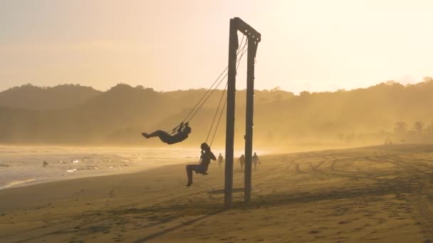 Moving Shot Two Friends Big Swing Misty Exotic Beach Sunset — Stock Video