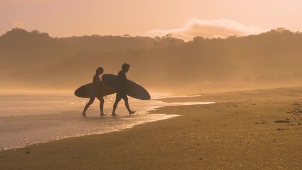 慢动作 日落冲浪后 一对冲浪者从水里跳了出来 两位朋友在Playa Venao冲浪地点的金光闪闪下参加了冲浪课程 在灿烂的阳光下拍摄的海滩生活 — 图库视频影像