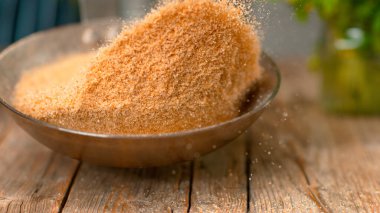 MACRO, DOF: Golden breadcrumbs are being toasted above a rustic wooden table in a hot metal pan. Unrecognizable chef roasting grated bread and golden crackers over an old wooden kitchen counter.