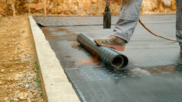 Close Opdrachtnemer Verbrandt Een Zwarte Rol Teerpapier Betonnen Fundering Mens — Stockfoto