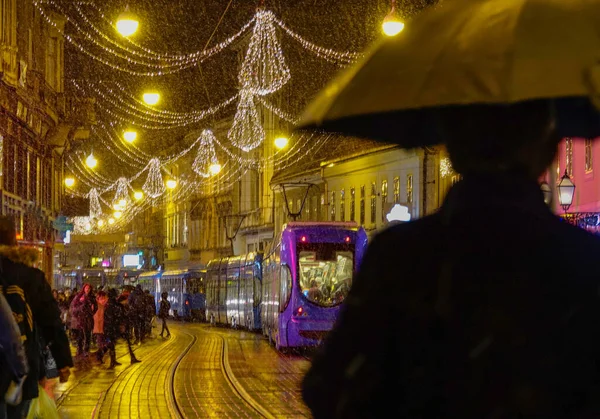 Dof 傘を持っている認識できない人は12月の雪の夜にお祭りの街を歩く 観光客は冬の完璧な夜に魅惑的な通りを探索します — ストック写真