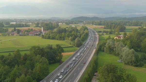 Aerial Lecąc Wzdłuż Długiego Korku Utworzonego Asfaltowej Autostradzie Przechodzącej Przez — Zdjęcie stockowe