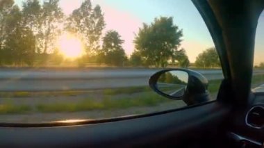 Yaklaş, LENS FlaRE: Ilık altın ışıklı kırsal manzarası boş bir otoyol boyunca seyir eden hareket eden bir spor araba penceresinden. Bir akşam saatlerinde kırsal alan manzarası