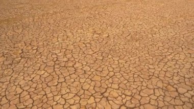 Uzun hava akımının yol açtığı çatlak arazinin havadan görünüşü. Kahverengi kurumuş toprak, toprak çatlakları ve bitki örtüsü yok. Kuru arazi, su eksikliğinden kaynaklanan çatlak desenli..