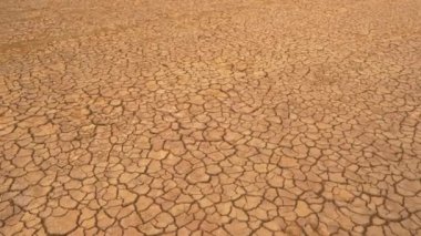Uzun hava akımının yol açtığı çatlak arazinin havadan görünüşü. Kahverengi kurumuş toprak, toprak çatlakları ve bitki örtüsü yok. Kuru arazi, su eksikliğinden kaynaklanan çatlak desenli..