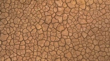 Uzun hava akımının yol açtığı çatlamış arazinin yukarıdan aşağı havadan görünüşü. Kahverengi kurumuş toprak, toprak çatlakları ve bitki örtüsü yok. Kuru arazi, su eksikliğinden kaynaklanan çatlak desenli..