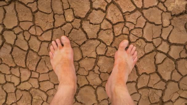 观察点 第一眼看到的是在一个裂开的沙漠地面上赤脚 旅行者站在干枯的土地上的泥泞的腿 赤脚站在旱地带裂缝的旱地上 — 图库视频影像
