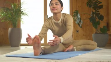 Genç Asyalı kadın diz boyu yoga pozisyonu sergiliyor. Filipinli kadın, mavi yoga minderinde vücut esnetiyor. Sağlıklı yaşam tarzı, canlılık ve doğal denge için yoga pratiği