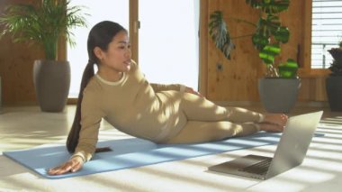 Asyalı kadın pilates koçu canlı yayında bacak kaldırma egzersizi öğretiyor. Genç ve fit Filipinli kadın spor giyim sektöründe online video kurslarında pilates çalışmalarını anlatıyor ve gösteriyor..