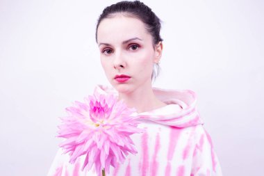 Pembe kapüşonlu kadın elinde pembe bir çiçek tutuyor.