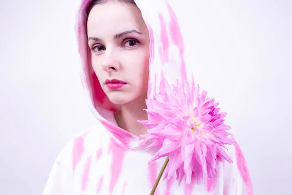 woman in a pink hoodie holding a pink flower