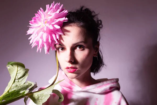 woman in a pink hoodie holding a pink flower