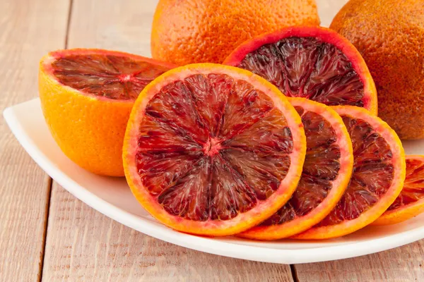 Ripe red blood oranges and slices in the plate — Stock Photo, Image