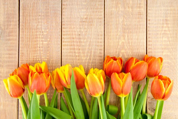Ramo de tulipanes amarillos y anaranjados sobre fondo de madera — Foto de Stock
