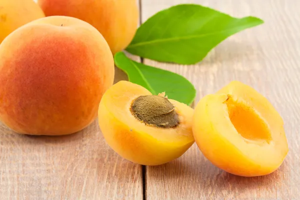 Ripe peaches and leaves on table — Stock Photo, Image