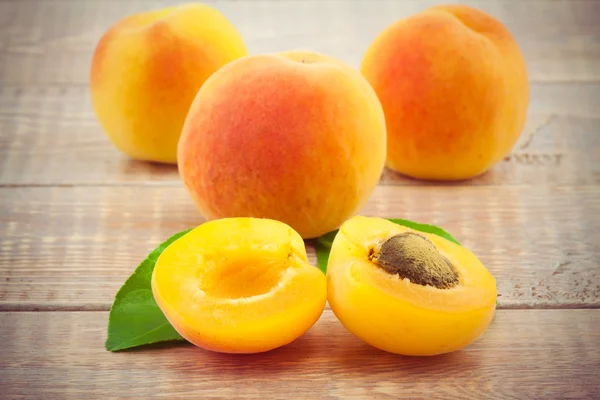 Ripe peaches with leaves on wooden table — Stock Photo, Image