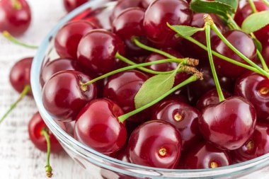 beyaz zemin üzerinde bir kabın içinde yapraklarla Olgun Kiraz