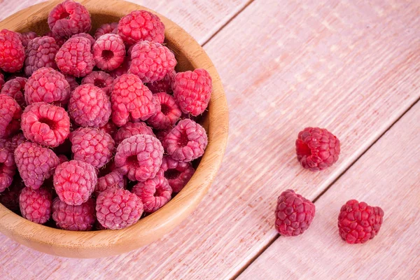 Fresh ripe raspberries in a bowl on a wooden background — Stock Photo, Image