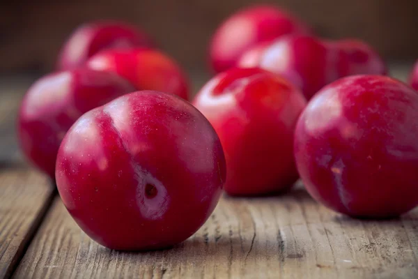 Red plums on old wooden background — Stock Photo, Image