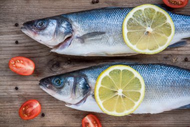 ahşap ba üzerine limon ve kiraz domates ile iki çiğ levrek balığı