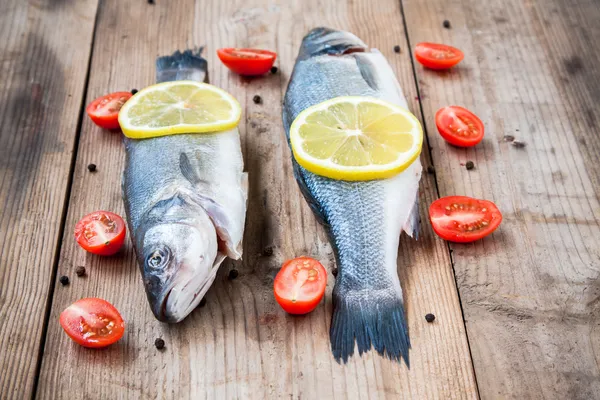 Due pesce crudo di mare con limone e pomodorini su ba di legno — Foto Stock