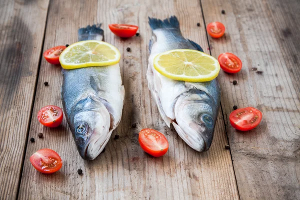 Due pesce crudo di mare con limone e pomodorini su ba di legno — Foto Stock