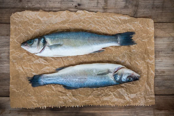 木製の背景に 2 つの生のシーバス魚 — ストック写真