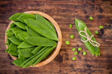 Genç yeşil bezelye pod ahşap zemin üzerine bir kase