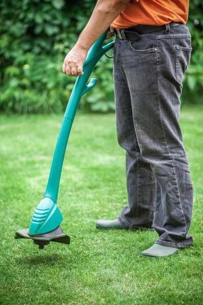 Homme tondre la pelouse avec tondeuse à herbe — Photo