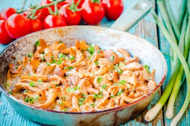 Kızarmış Cantharellus cibarius mantar ile bir tavada yeşil soğan