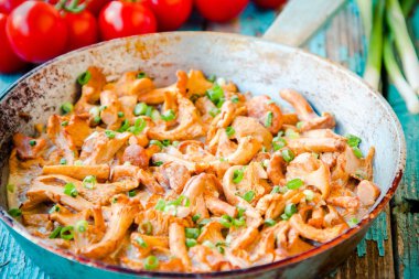 Kızarmış Cantharellus cibarius mantar ile bir tavada yeşil soğan