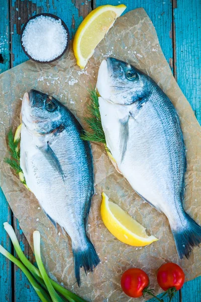Két nyers dorada halak, citrom, zöld hagyma és koktélparadicsommal — Stock Fotó