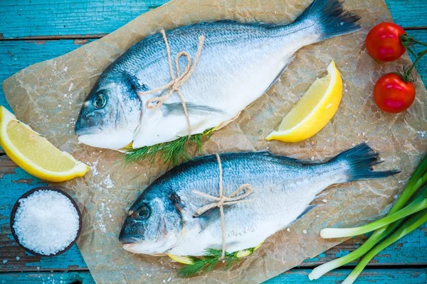 Two raw dorado fishes with lemon, green onions and cherry tomatoes — Stock Photo, Image