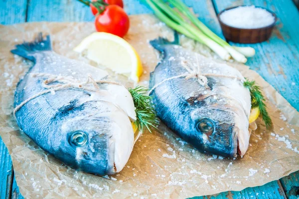 Two raw dorada fishes with lemon, green onions and cherry tomatoes — Stock Photo, Image