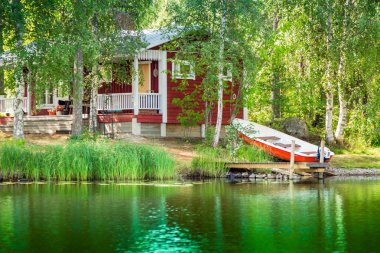 Old red Finnish summer cottage at a lake  clipart