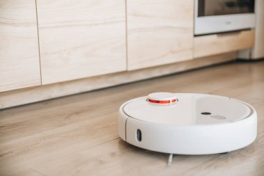 Modern mutfakta beyaz robotik süpürge zemini.
