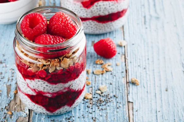 Chia Pudingi. Sağlıklı vanilyalı ahududu pudingi cam kavanozda taze böğürtlen ve ahşap arka planda granola yulaflı.