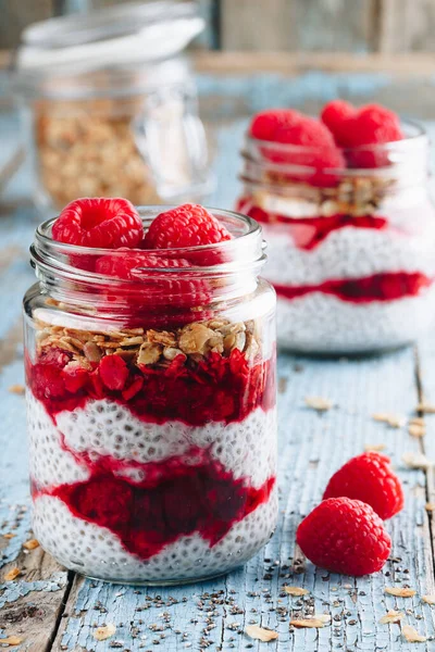 Chia Pudingi. Sağlıklı vanilyalı ahududu pudingi cam kavanozda taze böğürtlen ve ahşap arka planda granola yulaflı.