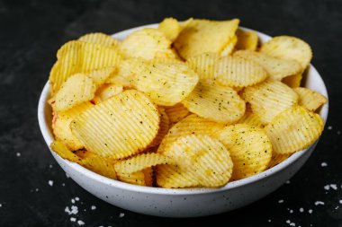 Patates cipsi. Kavrulmuş patates cipsi ve soğanlı ekşi krema. Koyu taştan bir arka planda, kopyalama alanı..