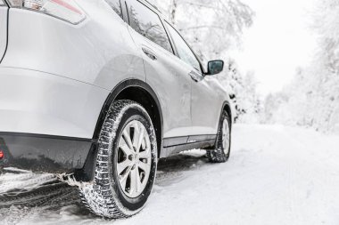 Car tire on a winter road in snow covered forest. Winter landscape with car on the road and trees covered with snow
