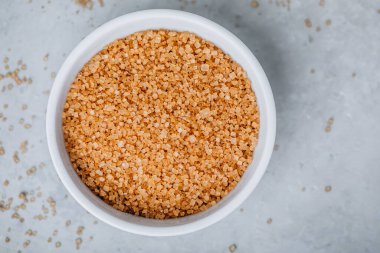 Esmer şeker. Esmer şeker gri taş arka planda beyaz kasede, üst görünümde.