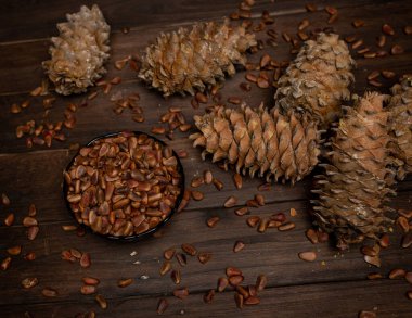 Çam kozalağı ve çam fıstığı tahta bir masada yatıyor..