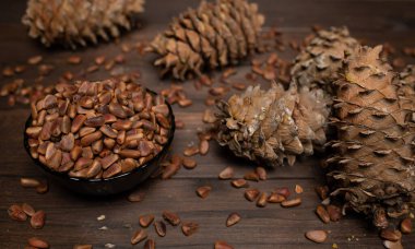 Çam kozalağı ve çam fıstığı tahta bir masada yatıyor..