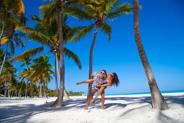 Homem dando passeio de piggyback para namorada na praia — Fotografia de Stock