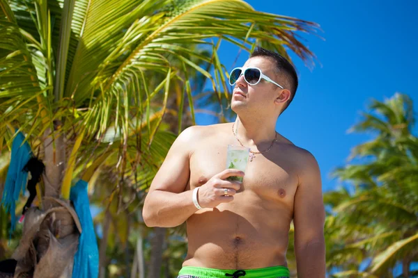 Jovem atraente na praia, tomando uma bebida — Fotografia de Stock