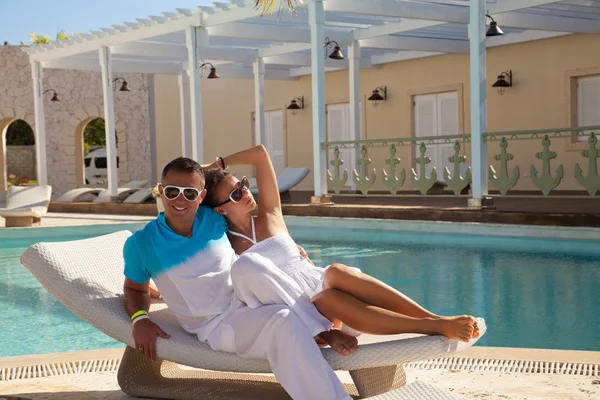 Sexy jovem casal relaxante perto da piscina em uma cama de praia — Fotografia de Stock